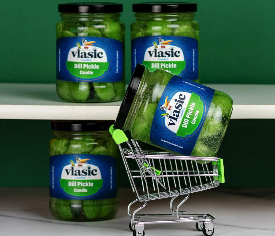 Four pickle candles that look like jars of pickles, one is in a tiny shopping cart