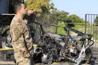 A Lebanese army officer stands next of a destroyed car in the southern town of Bazouriyeh, Lebanon, Saturday, Jan. 20, 2024. An Israeli drone strike on the car near the Lebanese southern port city of Tyre killed two people, the state-run National News Agency reported. (AP Photo/Mohammad Zaatari)