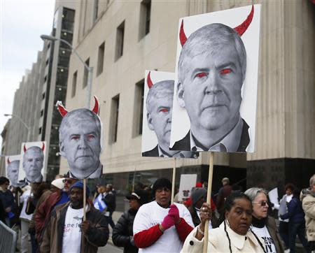 Protesters hold posters depicting Michigan Governor Rick Snyder as a devil, at a rally outside Theodore Levin U.S. Courthouse during Detroit's bankruptcy eligibility trial in Detroit, Michigan October 28, 2013. REUTERS/Rebecca Cook