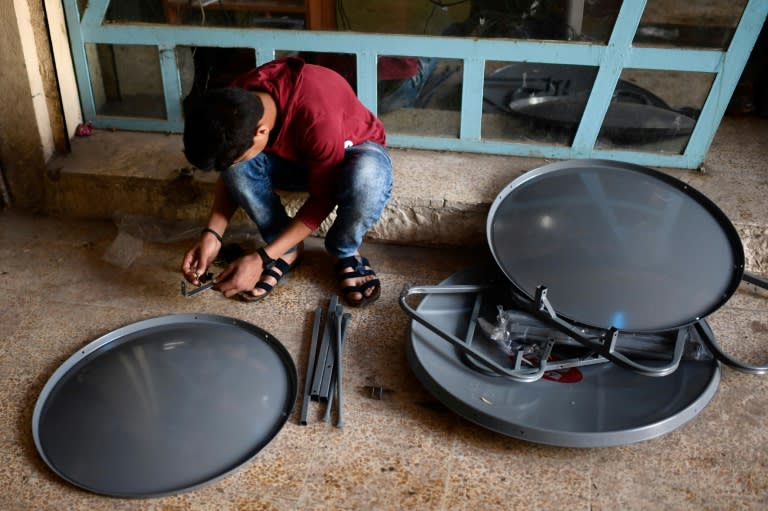 A young Iraqi prepares satellite dishes for sale at a market in east Mosul on April 15, 2017. Since Iraqi forces recaptured the sector from the Islamic State group in January, business has surged