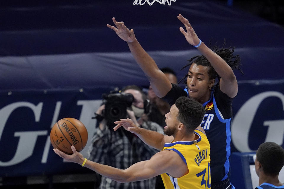 Golden State Warriors guard Stephen Curry (30) goes to the basket defender by Oklahoma City Thunder center Moses Brown, right, in the first half of an NBA basketball game Wednesday, April 14, 2021, in Oklahoma City. (AP Photo/Sue Ogrocki)