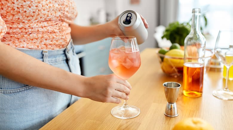 pouring a canned cocktail into a glass