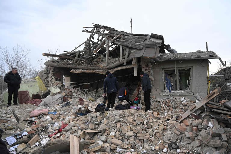 Varias personas buscan entre los escombros de una casa tras un ataque ruso en el pueblo de Velyka Vilshanytsia, a unos 50 km de Lviv, el 9 de marzo de 2023.
