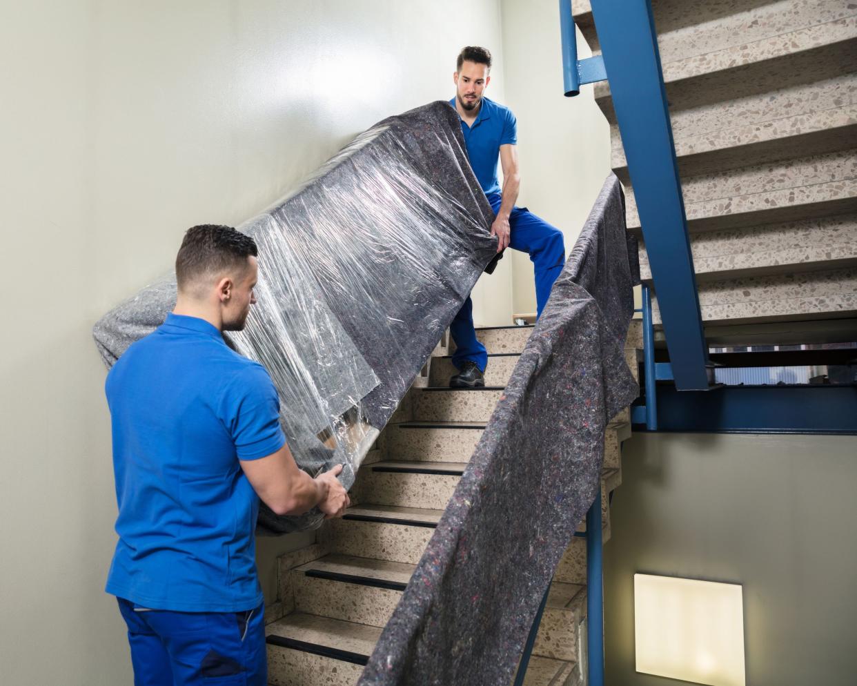 two movers carrying furniture on staircase