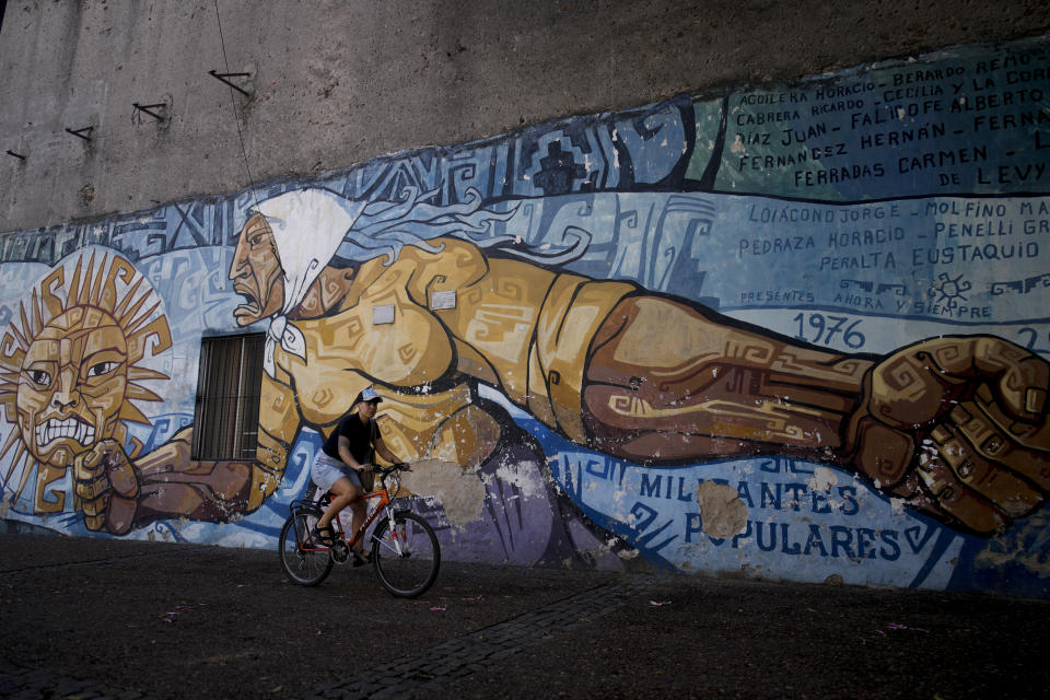 A cyclist rides past a mural honoring the Mothers of Plaza de Mayo in Buenos Aires, Argentina, Tuesday, March 19, 2024. The Mothers of Plaza de Mayo is a human rights organization created by women whose children were kidnapped by the military dictatorship that ruled Argentina from 1976 to 1983. (AP Photo/Natacha Pisarenko)