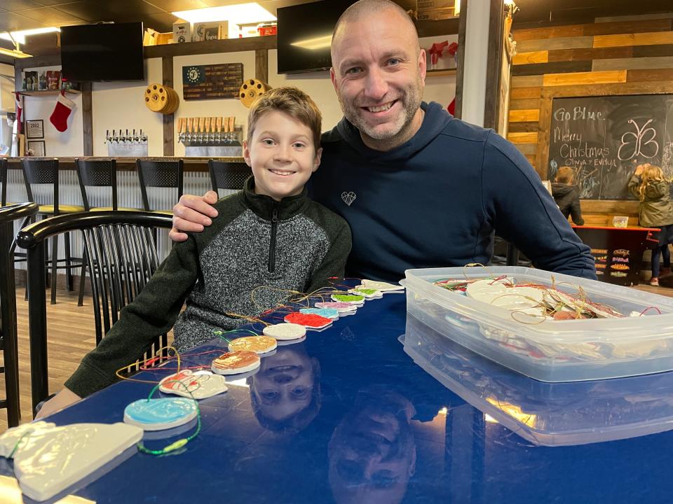 Evan Alford, 11, and Fund A Life founder Mark Howell display Christmas ornaments at Four Circles Brewery in Brighton on Tuesday, Dec. 5, 2023.