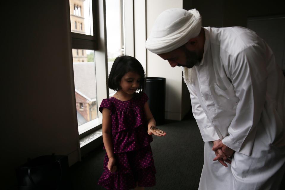 Madina (L) daughter of NYU Islamic Center Imam Khalid Latif (R) shows her Henna before Eid-ul-Fitr, a holiday celebrated by Muslims worldwide that marks the end of the Islamic holy month of fasting 'Ramadan' at Islamic Center of New York University in Manhattan borough of New York, United States on June 23, 2017.