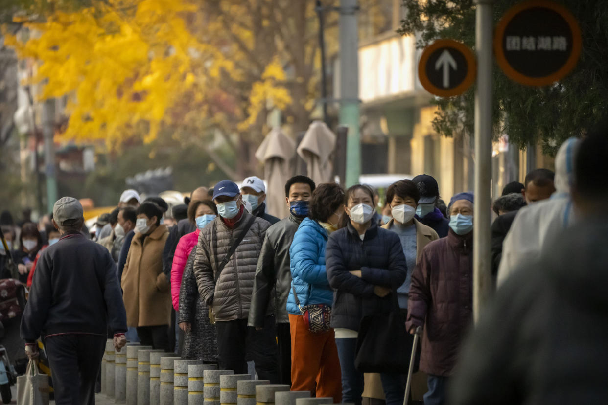 People wearing face masks wait for COVID-19 tests at a coronavirus testing site in Beijing, Thursday, Nov. 17, 2022. Chinese authorities faced more public anger Thursday after a second child's death was blamed on overzealous anti-virus enforcement, adding to frustration at controls that are confining millions of people to their homes and sparked fights with health workers. (AP Photo/Mark Schiefelbein)