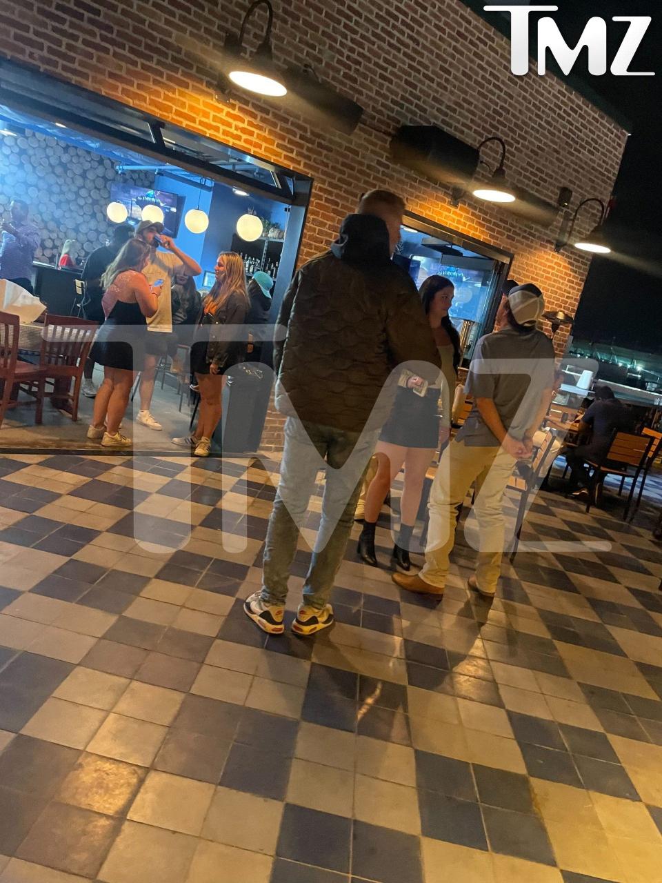 morgan wallen talking with a woman on a rooftop standing next to a table wiht three chairs