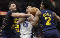 Orlando Magic's Markelle Fultz (20) drives between Cleveland Cavaliers' Larry Nance Jr. (22) and Collin Sexton (2) in the first half of an NBA basketball game, Friday, Dec. 6, 2019, in Cleveland. (AP Photo/Tony Dejak)