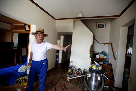 79-year-old local resident Isao Akutagawa, pauses as he tries to remove mud and debris from his house in a flood affected area in Mabi town in Kurashiki, Okayama Prefecture, Japan, July 12, 2018. Picture taken July 12, 2018. REUTERS/Issei Kato