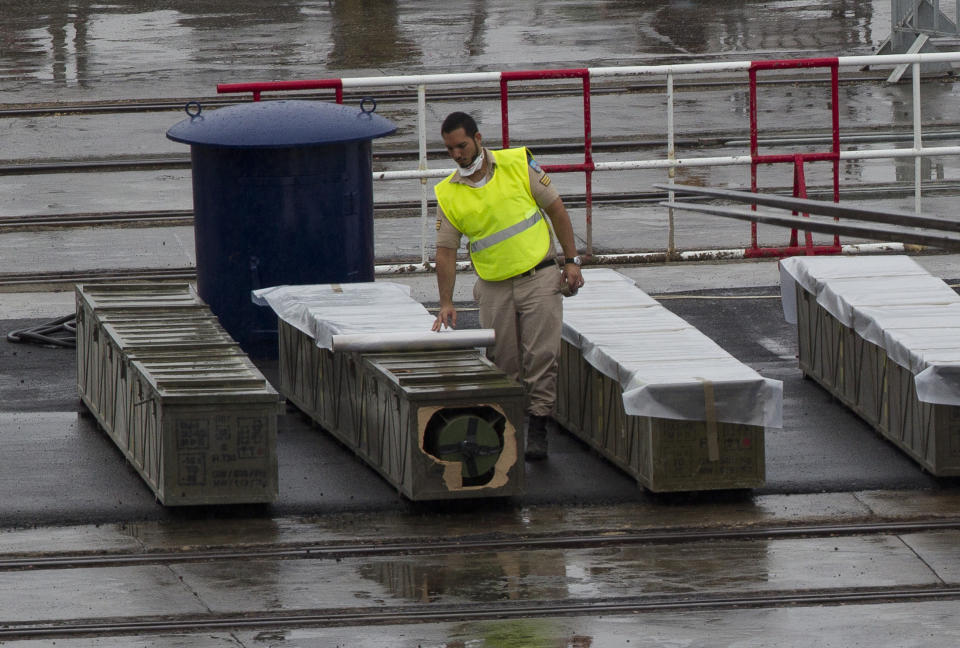 An Israeli soldier covers with plastic to protect from the rain, boxes containing missiles that the military unloaded from the seized Klos-C cargo ship in the military port of the Red Sea resort city of Eilat, southern Israel, Sunday, March 9, 2014. Israel's Prime Minister Benjamin Netanyahu is calling on the European Union's foreign policy chief, Catherine Ashton, currently visiting Tehran, to confront Iranian officials about the weapons Israel says it caught last week en route from Iran to militants in Gaza. Ashton is in Tehran to further negotiations with Iran about its nuclear program. (AP Photo/Ariel Schalit)