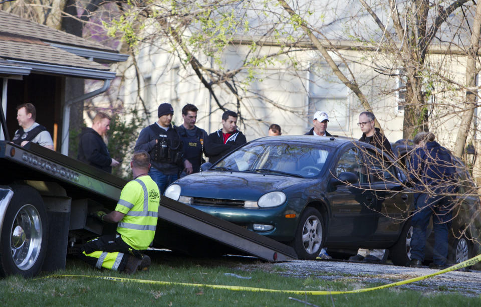 A car is removed by Kansas City police from the house, far right, of a Grandview man suspected in a series of shootings that have occurred on area roadways since early March, according to Police Chief Darryl Forté. He was arrested late Thursday, April 17, 2014, in the 6000 block of East 136th Street of Grandview, Mo., which is just east of Interstate 49 and south of the Three Trails Crossing area where seven shootings happened. (AP Photo/The Kansas City Star,Allison Long)