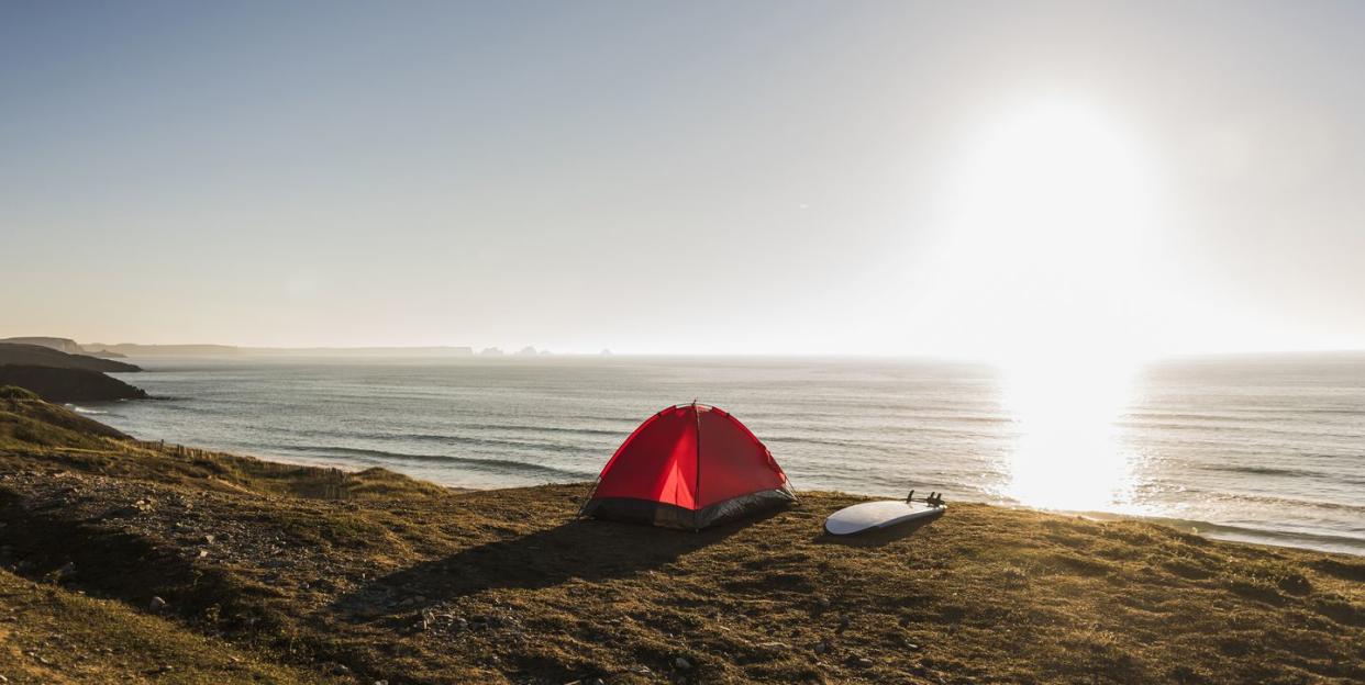 red tent and surfboard at seaside in the evening twilight