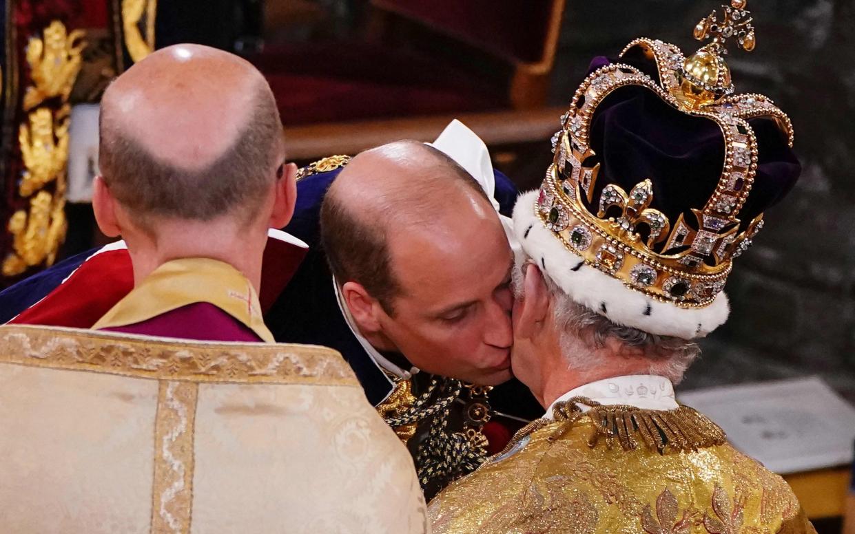 The Prince of Wales kisses his father, Britain's King Charles III, wearing St Edward's Crown, during the King's Coronation Ceremony