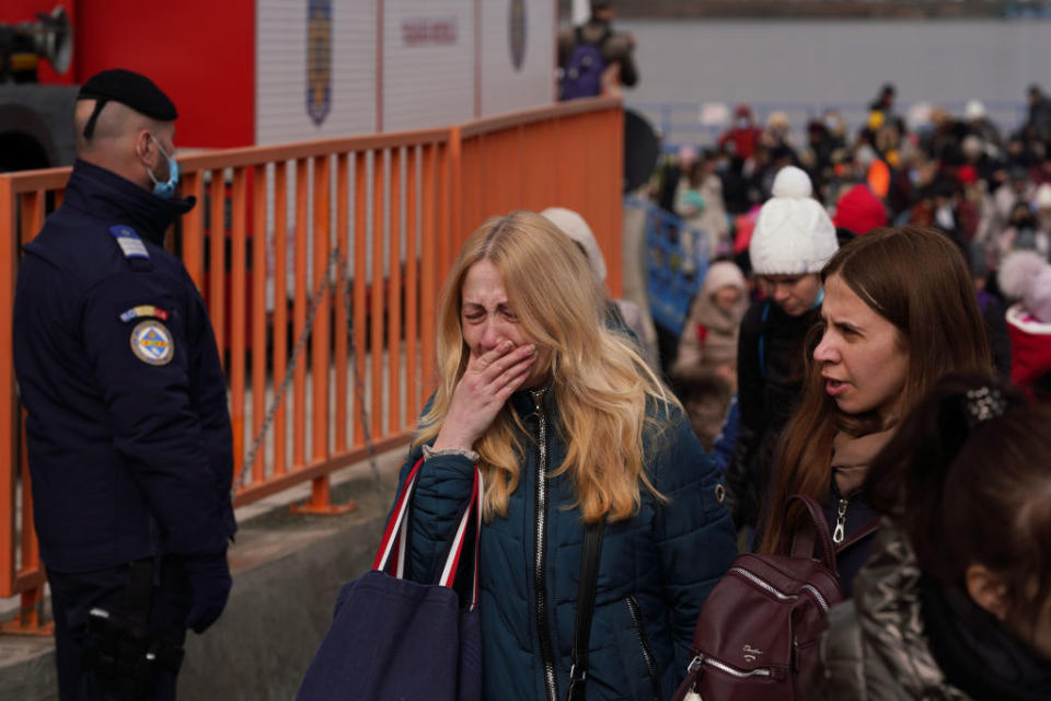 People who fled the conflict in Ukraine, some of them in tears, get off a ferry at a border crossing in Romania.