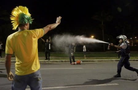 A police officer uses pepper spray during a protest against President Dilma Rousseff's appointment of former President Luiz Inacio Lula da Silva as her chief of staff, in front of the Brazilian national congress in Brasilia, Brazil, March 17, 2016. REUTERS/Ricardo Moraes