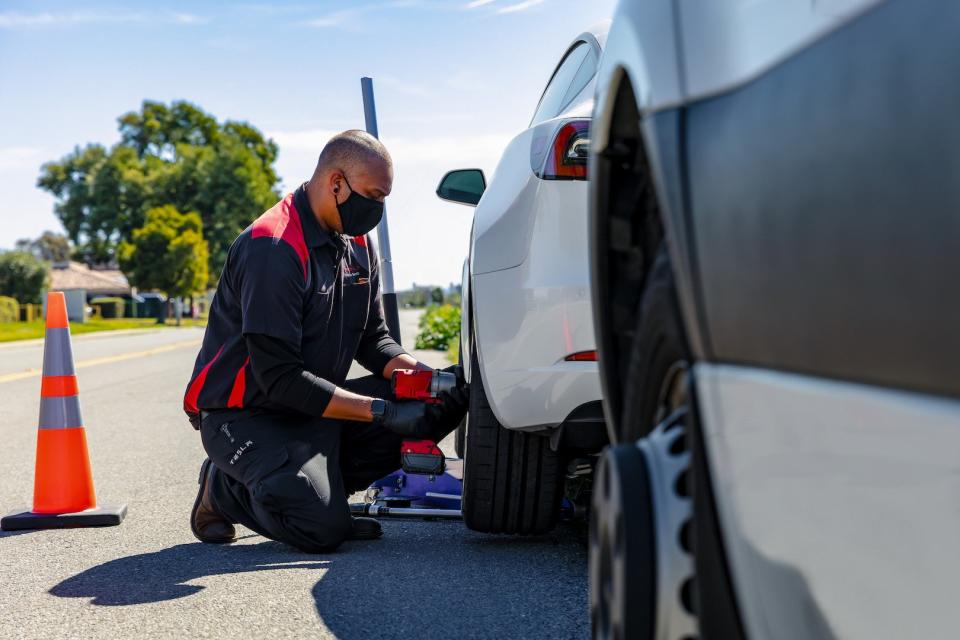 A Tesla technician changes a wheel by the roadside.