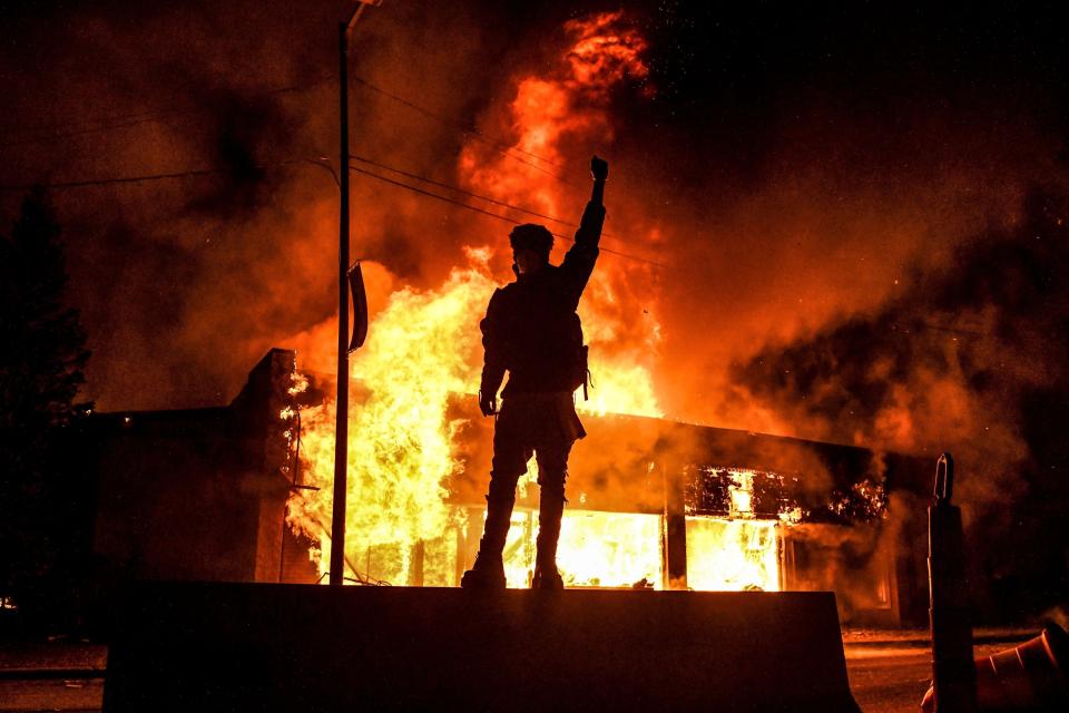 A protester stands in front of a burning building in Minneapolis on May 29, 2020, after the murder of George Floyd. (Photo: CHANDAN KHANNA/AFP via Getty Images)