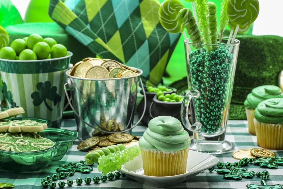 st patricks day activities table with green cupcakes, cookies, cups, and necklaces