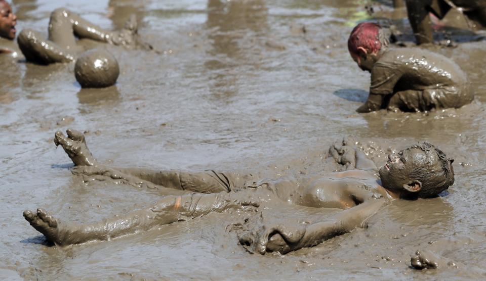 Nathan Jamerson, 10, wallows in the mud during Mud Day at the Nankin Mills Park, Tuesday, July 9, 2019, in Westland, Mich. The annual day is for kids 12 years old and younger. While parents might be welcome, this isn't an event meant for teens or adults. It's all about the kids having some good, unclean fun during their summer break and is sponsored by the Wayne County Parks. (AP Photo/Carlos Osorio)