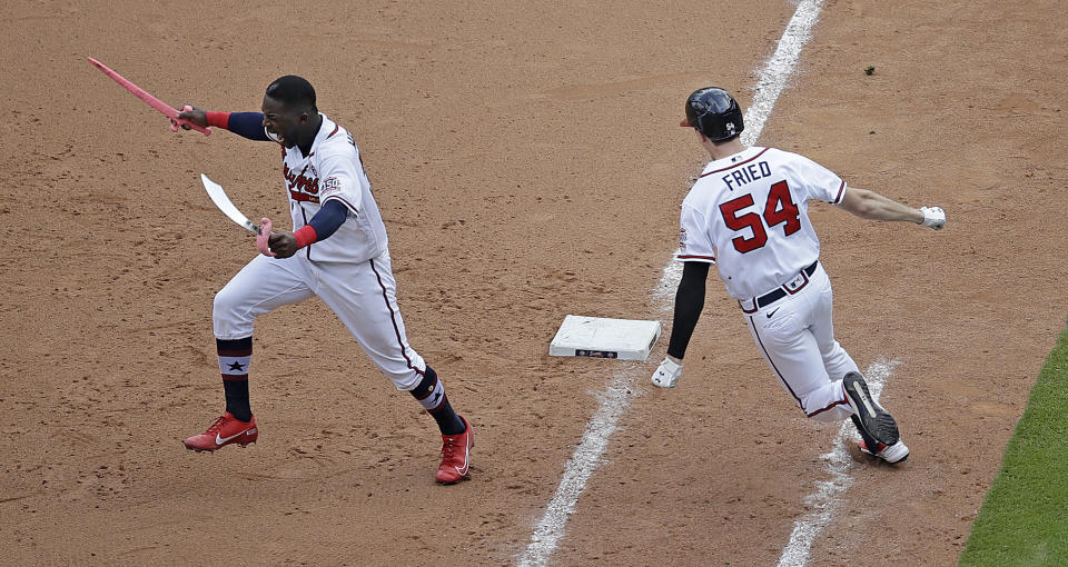 Atlanta Braves' Max Fried (54) rounds first base after making the winning hit against the Miami Marlins as Guillermo Heredia, left, storms the field during the 10th inning of a baseball game Sunday, July 4, 2021, in Atlanta. (AP Photo/Ben Margot)