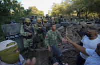 Residents who are fed up with the army’s strategy of simply separating the Jalisco and the Michoacan-based Viagras gangs, confront Mexican soldiers taking cover behind a barricade of car tires, in Loma Blanca, Mexico, Tuesday, Nov. 16, 2021. The residents, who are fed up with the army’s strategy of simply separating the Jalisco and the Michoacan-based Viagras gangs, want the army to either fight both cartels, or at least let the two gangs fight it out amongst themselves. (AP Photo/Eduardo Verdugo)