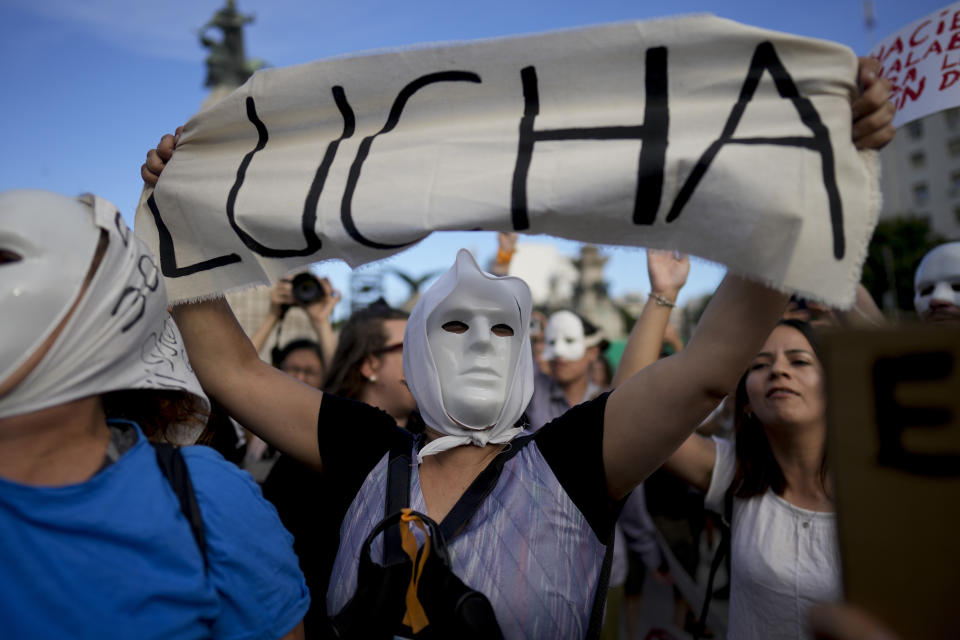 A woman wearing a mask holds a banner emblazoned with the Spanish word for fight, during a protest against measures regarding the cultural policies of President Javier Milei's government, in Buenos Aires, Argentina, Thursday, Jan. 4, 2024. (AP Photo/Natacha Pisarenko)