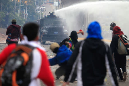 Supporters of Salvador Nasralla, presidential candidate for the Opposition Alliance Against the Dictatorship, throw rocks toward a police water cannon during a protest while awaiting for official presidential election results in Tegucigalpa, Honduras November 30, 2017. REUTERS/Jorge Cabrera