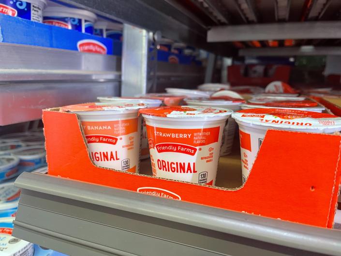 Red and white containers of yogurt in a cardboard display on a gray shelf