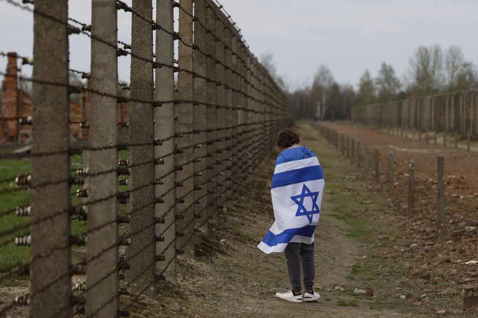 A man with an Israeli flag participates in the annual 'March of the Living', a trek between two former Nazi-run death camps, in Oswiecim, Poland, Tuesday, April 18, 2023 to mourn victims of the Holocaust and celebrate the existence of the Jewish state. (AP Photo/Michal Dyjuk)