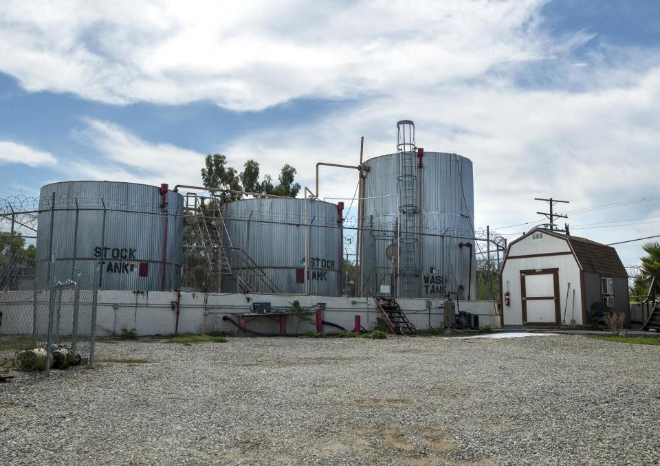 Oil storage tanks rise beside an oil drilling site.