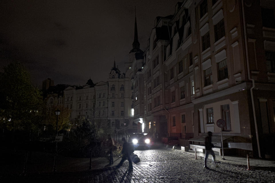 A car passes as city lighting turned off at twilight in Kyiv downtown, Ukraine, Monday, Oct. 31, 2022. Rolling blackouts are increasing across Ukraine as the government rushes to stabilise the energy grid and repair the system ahead of winter. (AP Photo/Andrew Kravchenko)