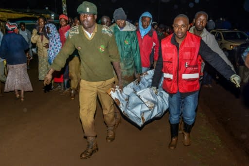 People carry a victim's body from a residential area on May 10, 2018 after the private Patel dam burst its bank at Solai, about 40 kilometres north of Nakuru, Kenya