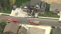 In this frame from video, emergency personnel work at the scene of a small plane that crashed into a house in Payson, Utah on Monday, Aug 13, 2018. Authorities said the pilot was killed in the crash. (John Wilson/KSL-TV/Deseret News via AP)