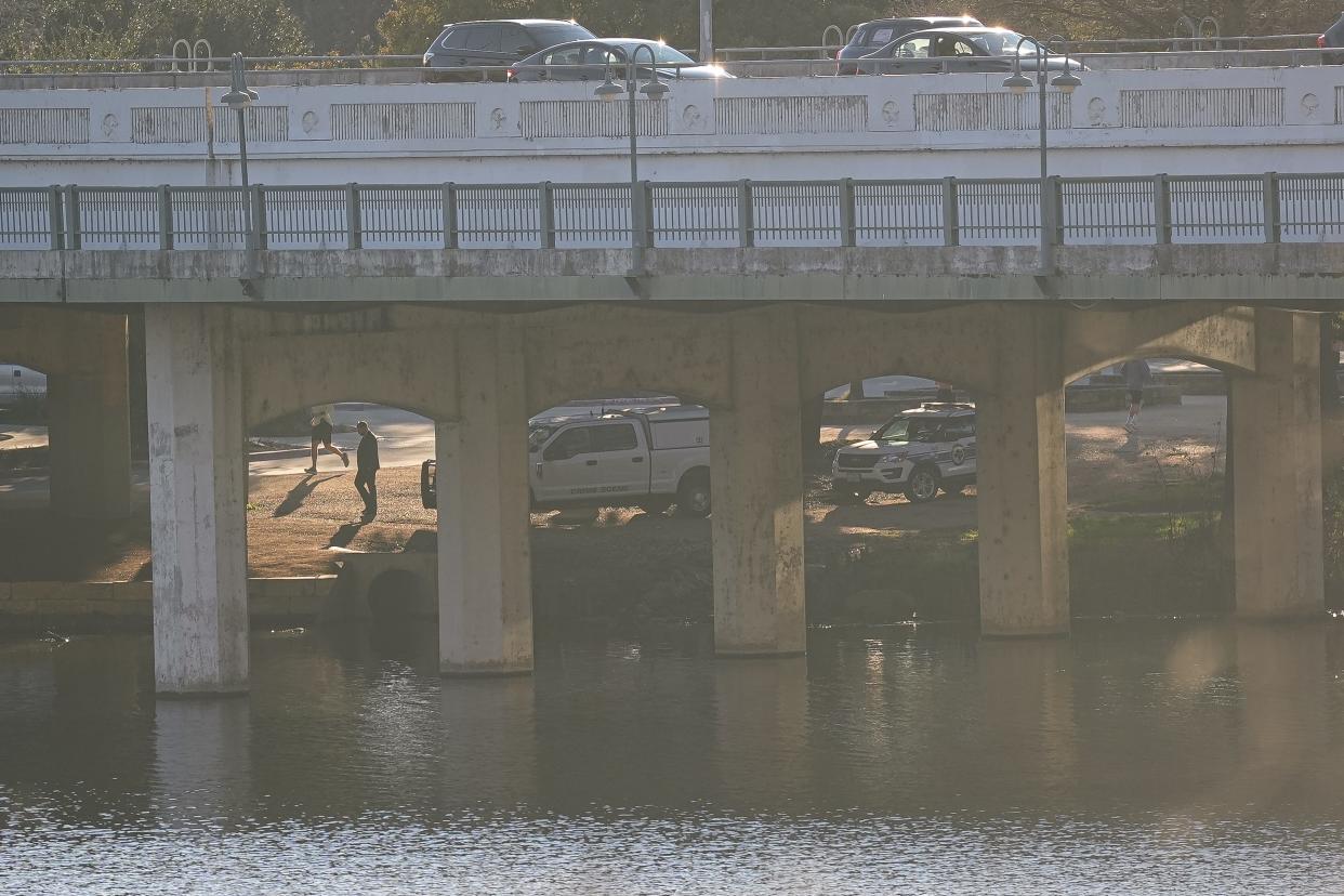 Austin Police Department crime scene investigation vehicles work underneath the First Street bridge on the opposite bank from where APD responded to a report of a body in Lady Bird Lake near Downtown Austin on Monday, Feb. 5, 2024.