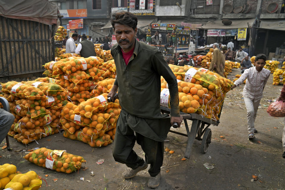 A laborer works in a wholesale fruit and vegetable market in Lahore, Pakistan, Friday, Feb. 17, 2023. Many laborers are worried how they will survive after the government advanced a bill to raise 170 billion rupees in tax revenue. That could worsen impoverished Pakistan's economic outlook as it struggles to recover from devastating summer floods and a wave of violence. (AP Photo/K.M. Chaudary)