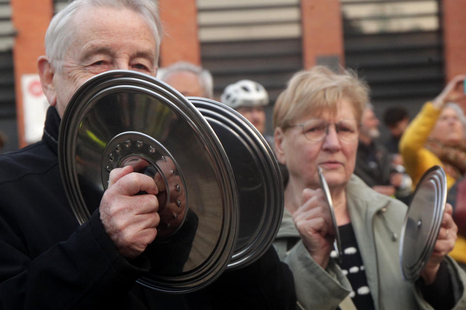 People bang pots and pans while French President Emmanuel Macron seeks to diffuse tensions in a televised address to the nation, Monday, April 17, 2023 in Lille, northern France. French President Emmanuel Macron said Monday that he heard people's anger over raising the retirement age from 62 to 64, but insisted that it was needed. In an televised address to the nation, Macron said "this changes were needed to guarantee everyone's pension," after he enacted the pension law on Saturday. (AP Photo/Michel Spingler)