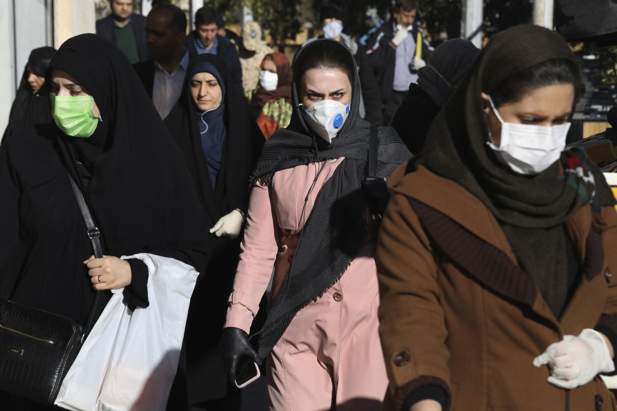 Unas personas con mascarillas caminan sobre una acera en el centro de Teherán, Irán, el lunes 2 de marzo de 2020. (AP Foto Vahid Salemi)