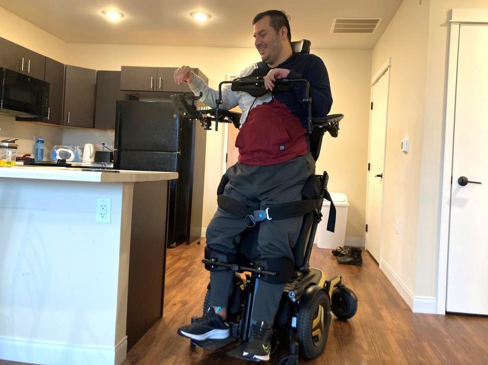 Arif Faizi, 34, demonstrates the standing function of his motorized wheelchair, which helps relieve painful muscle spasms in his legs. A donation from Kyle Weatherly, a University of Wisconsin regent, made it possible for Faizi to receive the specialized chair, which is not usually covered by insurance.