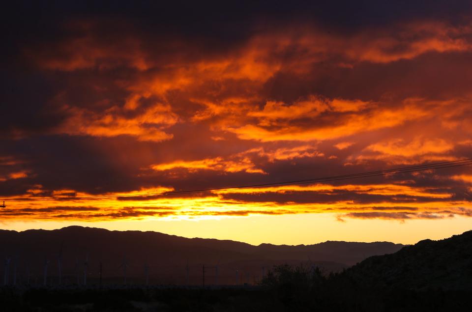 The sun illuminates the clouds from below as is rises in Palm Springs, Calif., the morning of March 30, 2024. Rain is expected in the Coachella Valley today.