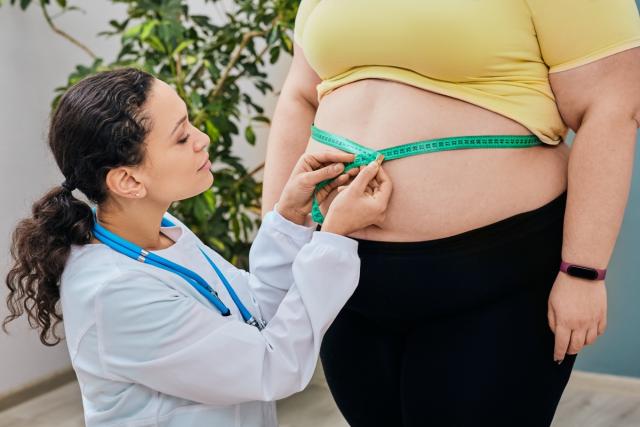 Woman measuring waist with measuring tape,Excess belly fat and