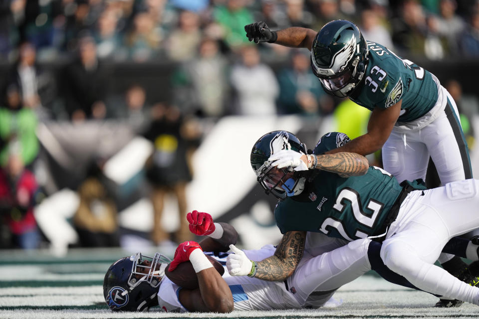 Tennessee Titans' Treylon Burks lies on the field after scoring a touchdown during the first half of an NFL football game in front of Philadelphia Eagles' Marcus Epps and Eagles' Josiah Scott, top, Sunday, Dec. 4, 2022, in Philadelphia. (AP Photo/Matt Slocum)