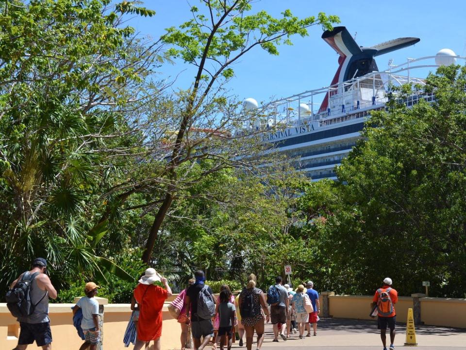 Passengers walk back to the Carnival Vista at the Mahogany Bay cruise port.