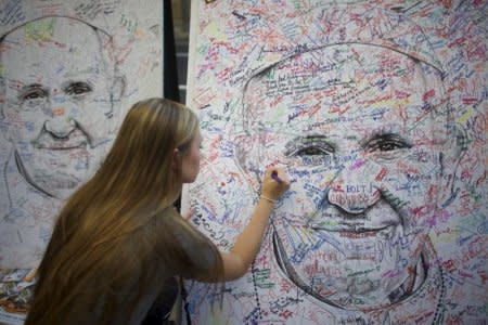 Casey Kretsch, 20, from Minnesota, a pilgrim attending the World Meeting of Families, signs a poster drawing of Pope Francis, by artist Mark Gaines, in Philadelphia, Pennsylvania, September 23, 2015.  REUTERS/Mark Makela