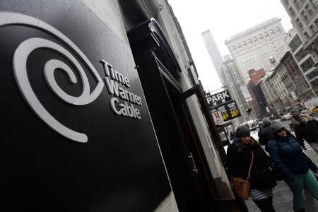 Pedestrians walk past a Time Warner Cable customer service center in New York February 13, 2014. REUTERS/Joshua Lott