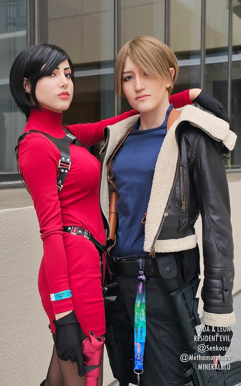 An Ada Wong cosplayer throws her armor over the shoulder of a Leon Kennedy cosplayer.