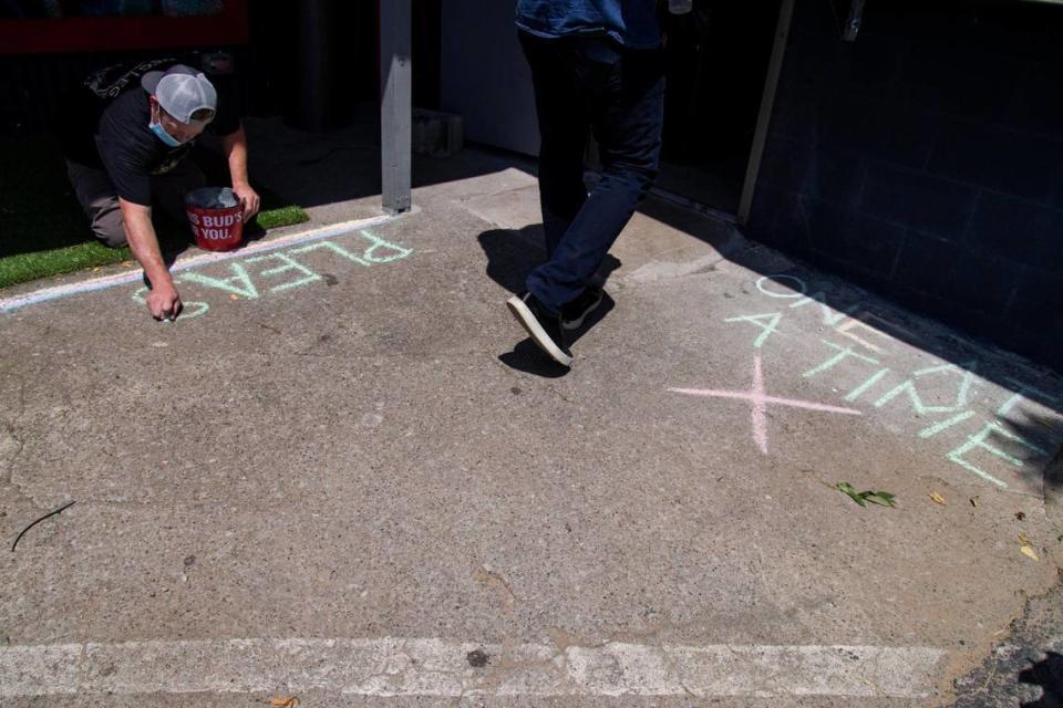 Phillip Cronin, who owns Kismet with his wife, Tonya Mays-Cronin, draws with chalk outside of the restaurant’s ordering window to specify where customers should stand in line, at distances of six feet apart, to order their food. The restaurant Kismet opens at the Burl in Lexington, Ky. on June 10, 2020. The COVID-19 pandemic halted typical functioning of restaurants and delayed the opening of new restaurants as a result of stay-at-home orders and non-essential business closures. With Kentucky entering phase 2 of reopening, Kismet was able to open its doors to patrons, offering outside dining and limited seating to maintain social distancing protocol. Mays-Cronin says she is “most excited to see the community out to enjoy their food.”
