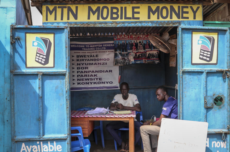 In this photo taken Tuesday, Sept. 10, 2019, a man sits in his mobile money kiosk which specializes in sending money from South Sudan to Uganda, in the capital Juba, South Sudan. South Sudan has launched mobile money, the ability to send and receive funds by phone, in an attempt to boost the economy after a five-year civil war killed almost 400,000 people. (AP Photo/Sam Mednick)