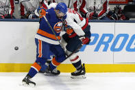 New York Islanders defenseman Adam Pelech (3) checks Washington Capitals right wing Garnet Hathaway (21) against the boards during the first period of an NHL hockey game Thursday, April 22, 2021, in Uniondale, N.Y. (AP Photo/Kathy Willens)